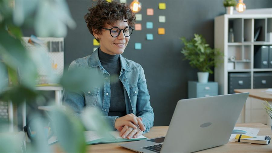 Une étudiante souriante devant son ordinateur portable