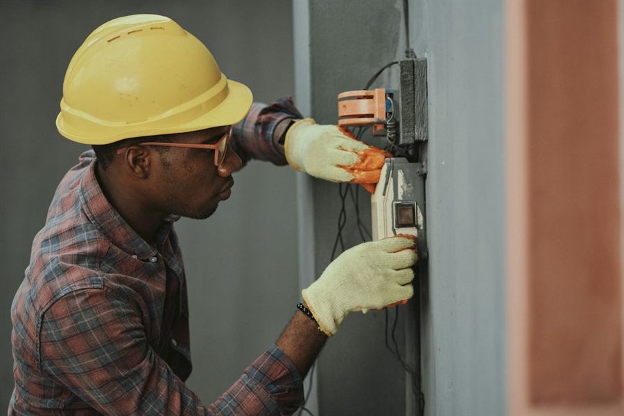 Un électricien installe un câblage, casque de chantier sur la tête